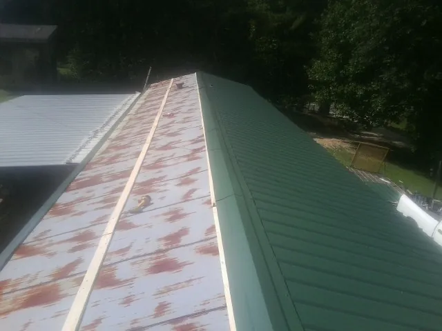 Old rusted panels beside newly installed green metal roofing — Wind Damage Roof Repair by Roofing Brothers in Medford